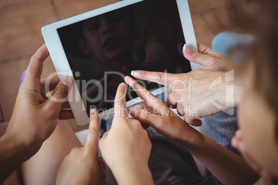 Family pointing their fingers at digital tablet