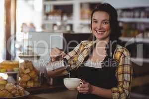 Portrait of waitress making cup of coffee at counter