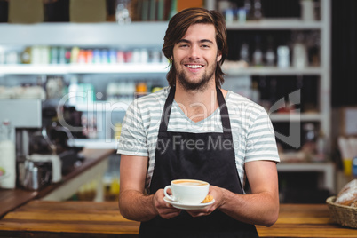 Portrait of waiter offering a cup of coffee