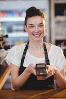 Smiling waitress showing credit card machine