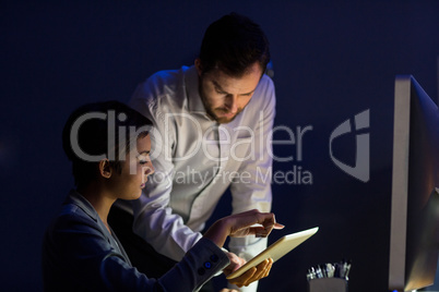 Businesswoman discussing with colleague over digital tablet