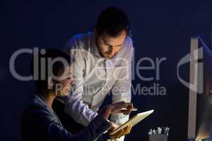 Businesswoman discussing with colleague over digital tablet