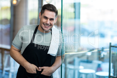 Smiling waiter leaning on glass door in cafÃ?Â©