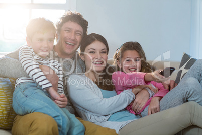 Family watching television while sitting on sofa