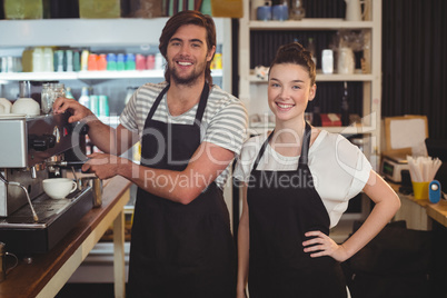 Portrait of waiter and waitress making cup of coffee at counter