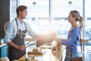 Waiter giving parcel to customer at counter