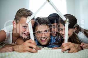 Happy family playing with model house in bedroom