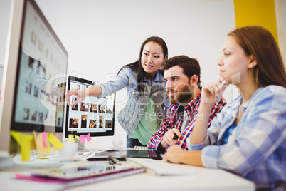 Businesswoman showing computer screen to coworkers