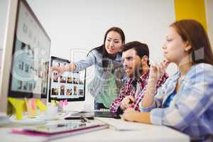 Businesswoman showing computer screen to coworkers