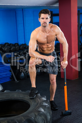 Shirtless young athlete with sledgehammer in gym