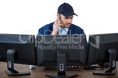 Security officer listening to earpiece while using computer