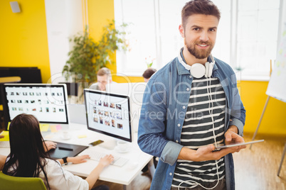 Portrait of happy executive using digital tablet at creative office