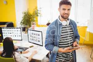 Portrait of happy executive using digital tablet at creative office