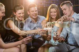 Group of smiling friends sitting on sofa and having a glass of champagne