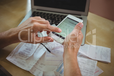 Man calculating bills on mobile phone