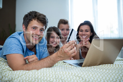 Family doing online shopping on laptop in bedroom at home