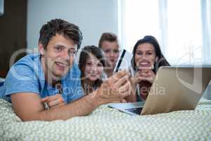 Family doing online shopping on laptop in bedroom at home