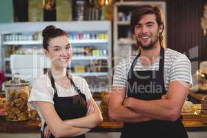 Waiter and waitress standing with arms crossed in cafe