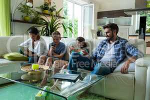 Family using laptop and mobile phone in living room