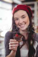 Portrait of smiling woman holding cupcake