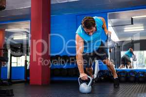 Fit young man holding kettlebells in gym