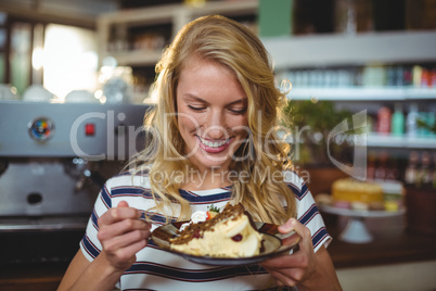 Smiling woman eating dessert in cafe