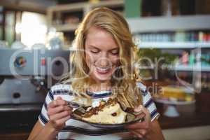 Smiling woman eating dessert in cafe