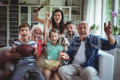 Happy multi-generation family watching soccer match on television in living room