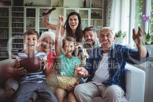 Happy multi-generation family watching soccer match on television in living room