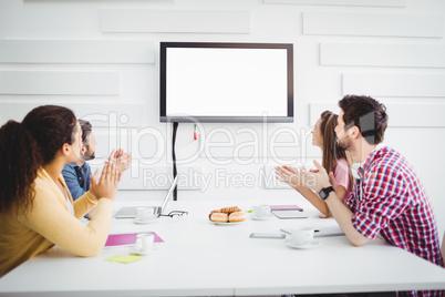 Happy colleagues applauding during meeting at creative office