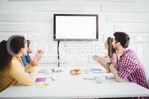 Happy colleagues applauding during meeting at creative office