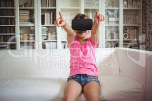 Happy girl looking through virtual reality headset in living room