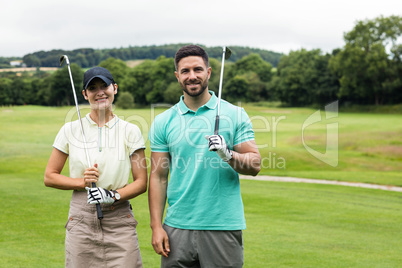 Couple standing with golf club in golf course