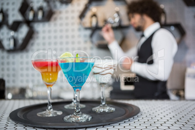 Various cocktails on a serving tray in bar counter