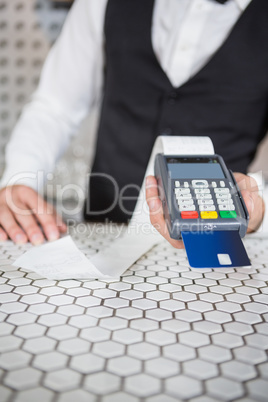 Bartender accepting a credit card at bar counter