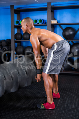 Side view of male athlete picking up tire