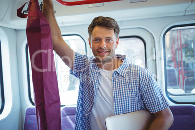 Handsome man holding laptop while travelling in train