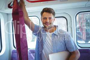 Handsome man holding laptop while travelling in train