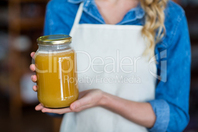 Mid-section of female staff holding jar of honey