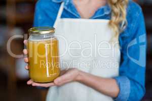 Mid-section of female staff holding jar of honey