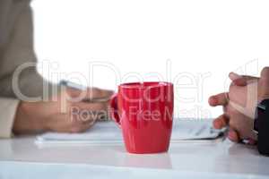 Businesswomen writing on clipboard with coffee mug on desk