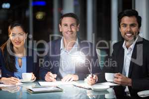 Group of businesspeople smiling at camera while having coffee