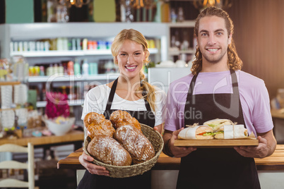 Portrait of waiter and waitress holding a tray of bread and meal