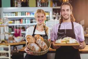 Portrait of waiter and waitress holding a tray of bread and meal