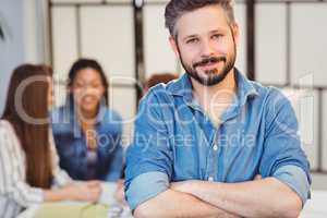 Businessman with arms crossed against female coworkers