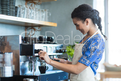 Waitress making cup of coffee in cafe