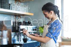 Waitress making cup of coffee in cafe