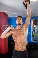 Shirtless athlete exercising with kettlebells