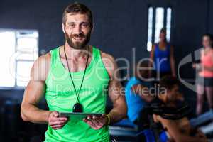 Portrait of happy hipster holding tablet in gym
