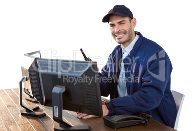 Happy Security officer talking on walkie-talkie while using computer